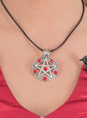 Eine silberne Pentagramm-Kette mit roten Steinen und einer schwarzen Kordel ziert den Hals der Trägerin; ihre roten Steine heben sich wunderschön von roter Kleidung ab – ein auffälliges Stück Pentagramm-Schmuck, ideal für jedes Hexenkostüm.