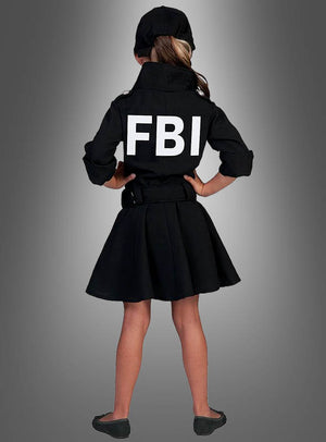 Ein junges Mädchen steht mit dem Rücken zur Kamera und trägt das FBI-Uniformkleid für Mädchen – ein authentisch wirkendes schwarzes Kleid mit Jacke, auf dessen Rücken „FBI“ prangt, was es zur idealen Wahl als FBI-Kleid für Kinder oder als Kriminalpolizistin-Kostüm macht –, dazu eine passende Mütze und schwarze Schuhe, vor einem grauen Hintergrund mit Farbverlauf.