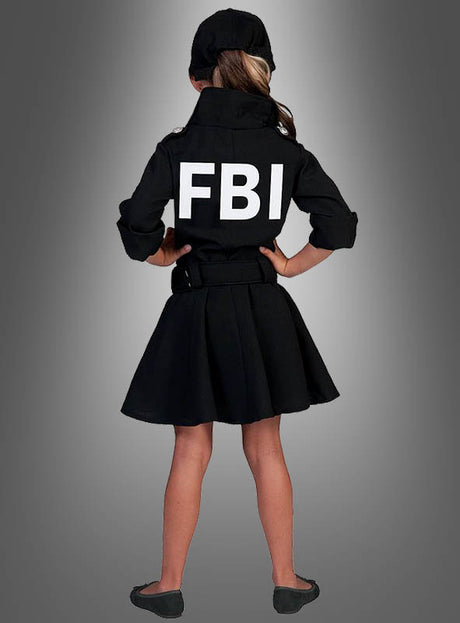 Ein junges Mädchen steht mit dem Rücken zur Kamera und trägt das FBI-Uniformkleid für Mädchen – ein authentisch wirkendes schwarzes Kleid mit Jacke, auf dessen Rücken „FBI“ prangt, was es zur idealen Wahl als FBI-Kleid für Kinder oder als Kriminalpolizistin-Kostüm macht –, dazu eine passende Mütze und schwarze Schuhe, vor einem grauen Hintergrund mit Farbverlauf.