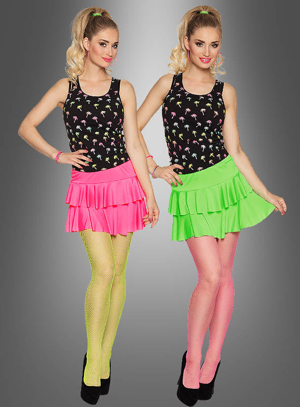 Zwei Frauen, die identische schwarze Oberteile mit Palmenmuster und Neon-Miniröcke mit Volants tragen – die eine in einem rosa Rock mit gelben Strumpfhosen, die andere in einem grünen Rock mit rosa Strumpfhosen –, beide in schwarzen Pumps, stehen nebeneinander.