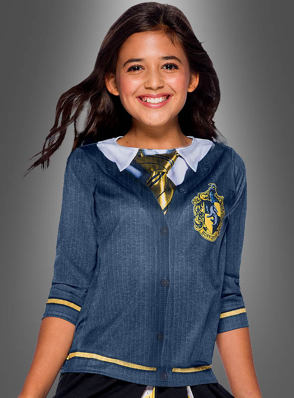 Lächelndes Mädchen in einem schwarz-gelben „Kinder Hufflepuff“-Shirt aus der Harry-Potter-Reihe, mit Krawatte, Hemd mit Kragen und Wappen, vor einem grauen Hintergrund mit Farbverlauf.