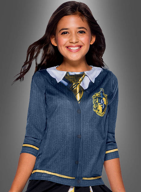 Lächelndes Mädchen in einem schwarz-gelben „Kinder Hufflepuff“-Shirt aus der Harry-Potter-Reihe, mit Krawatte, Hemd mit Kragen und Wappen, vor einem grauen Hintergrund mit Farbverlauf.