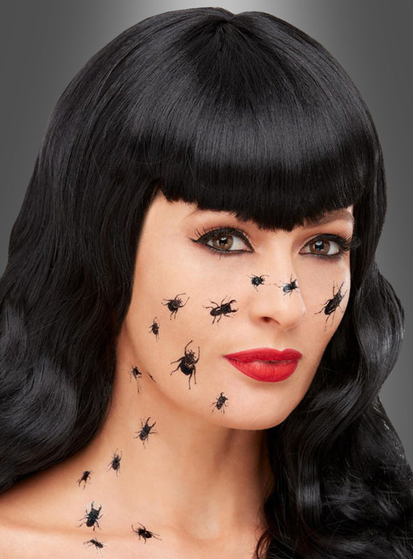 Eine Frau mit langen schwarzen Haaren und rotem Lippenstift hat realistisch wirkende, schaurige kleine Käfer als Tattoos im Gesicht und am Hals vor einem grauen Hintergrund, was eine eindrucksvolle Halloween-Illusion erzeugt.