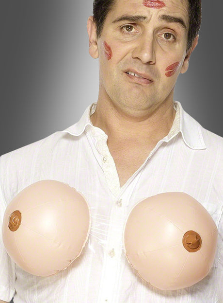 Ein Mann mit Lippenstiftflecken im Gesicht trägt ein weißes Hemd und die „Aufblasbare Brüste Männerballett“-Kostüme und steht vor einem grauen Hintergrund – perfekt für ein lustiges Männerballett oder einen unvergesslichen Junggesellenabschied.