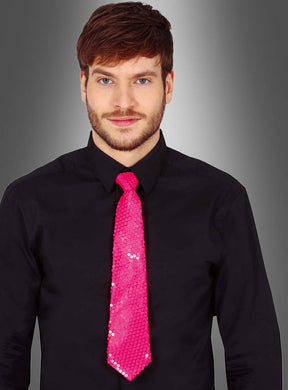 Ein Mann in einem schwarzen Hemd und einer leuchtend pinkfarbenen Pailletten-Krawatte „Neon“, der vor einem grauen Hintergrund mit Farbverlauf steht.