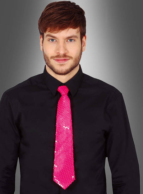 Ein Mann in einem schwarzen Hemd und einer leuchtend pinkfarbenen Pailletten-Krawatte „Neon“, der vor einem grauen Hintergrund mit Farbverlauf steht.