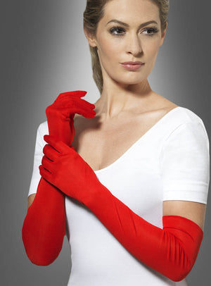 Eine Frau trägt ein weißes Oberteil und die „Handschuhe 50 cm extra lang“ in leuchtendem Rot und posiert vor einem neutralen grauen Hintergrund, wobei sie mit einer Hand den anderen Handschuh berührt.