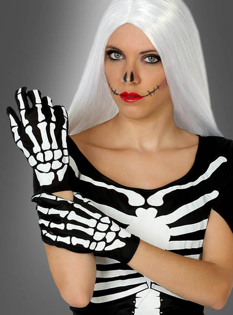 Eine Frau mit langen weißen Haaren in einem Skelettkostüm und Skelett-Handschuhen für Damen und Herren, mit Skelett-Make-up an Nase und Mund, posiert vor einem grauen Hintergrund – ein auffälliges Halloween-Kostüm, das sich perfekt für jede gruselige Feier eignet.