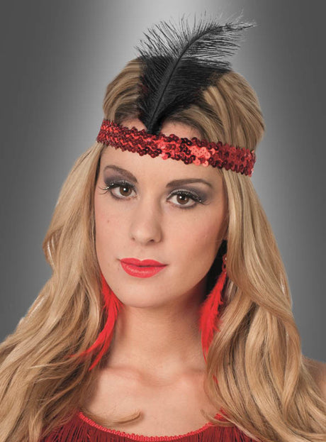 Eine Frau mit langen blonden Haaren, die den Haarschmuck im Stil der 20er Jahre mit schwarzer Feder trägt – ein rotes Charleston-Haarband mit Pailletten, verziert mit einer schwarzen Feder, sowie dazu passende rote Federohrringe –, blickt vor einem grauen Hintergrund direkt in die Kamera – ein auffälliges Flapper-Accessoire.