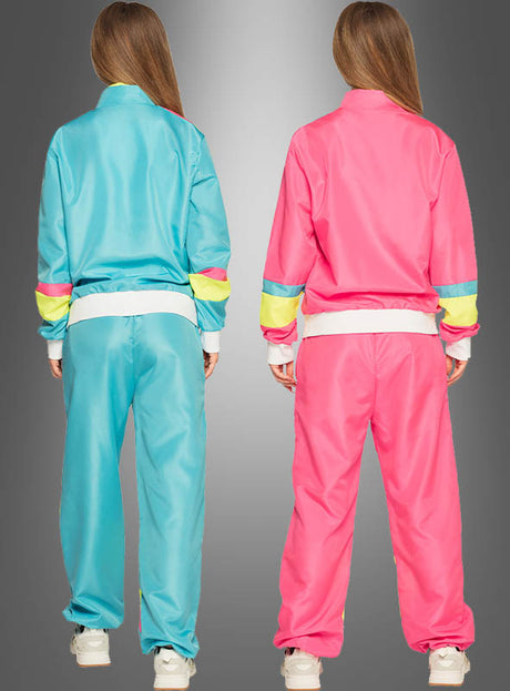 Zwei Personen stehen nebeneinander, mit dem Rücken zum Betrachter, und tragen lockere Trainingsanzüge im Neon-Stil der 80er Jahre – einer in Blau mit gelben und rosa Streifen, der andere in Rosa mit gelben und blauen Streifen – vor einem grauen Hintergrund mit Farbverlauf.