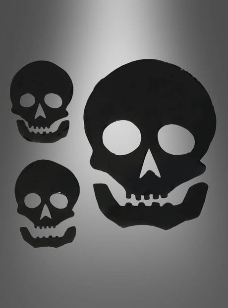 Drei schwarze Totenkopf-Silhouetten in verschiedenen Größen heben sich von einem grauen Hintergrund mit Farbverlauf ab und sind damit eine auffällige Wahl für Ihre „Halloween-Fensterdekoration aus Gel-Kürbis oder Totenkopf“.
