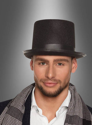 Ein Mann mit kurzem Bart trägt einen klassischen schwarzen Zylinder und einen karierten Frack über einem weißen Hemd und steht vor einem grau verlaufenden Hintergrund – ein Outfit, das perfekt für alle ist, die auf der Suche nach eleganten Karnevalskostümen sind.