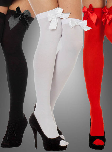 Drei Paar Overknee-Strümpfe – „Sexy Overknees mit Schleife“ in Schwarz, Weiß und Rot –, jeweils mit einer großen Satinschleife verziert und zusammen mit High Heels vor grauem Hintergrund in Szene gesetzt. Das ideale Accessoire für ein Karnevalskostüm.