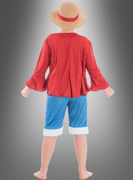 Ein Kind, das ein „Ruffy“-Kostüm von „Kinder One Piece“ trägt – bestehend aus einem Strohhut, einem roten Langarmhemd und blauen Shorts –, steht barfuß vor einem Hintergrund mit Farbverlauf und ist mit dem Rücken zur Kamera gewandt.