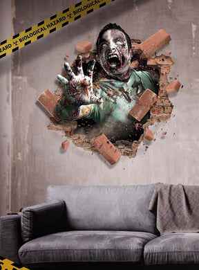 Ein Zombie bricht durch eine Backsteinwand über einer grauen Couch im Wohnzimmer, in dessen Ecke ein „Biological Hazard“-Band zu sehen ist – eine auffällige Halloween-Dekoration mit dem „Großen Wandbild 70 x 80 cm Halloween-Deko“, perfekt als Horror-Wandaufkleber und selbstklebendes Wandbild für eine wahrhaft gruselige Atmosphäre.