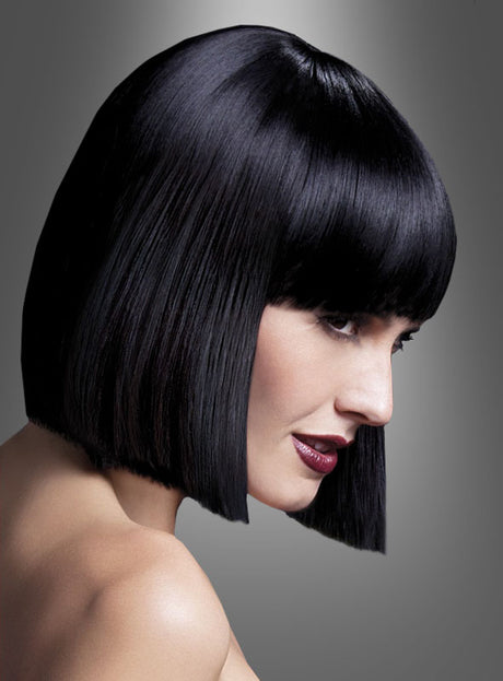 Person mit einer kurzen, glatten, glänzenden schwarzen „Lola Perücke Deluxe“ im Pagenschnitt-Bob-Stil und einem geraden Pony, im Profil vor einem grauen Hintergrund mit Farbverlauf abgebildet.
