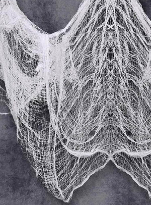 Ein riesiges Dekotuch aus Stoff im Format 2 x 5 Meter, das an klassische weiße Gaze erinnert, ist vor einem grauen, strukturierten Hintergrund drapiert, wobei locker gewebte Fäden in schichtartigen, netzartigen Mustern herabhängen.