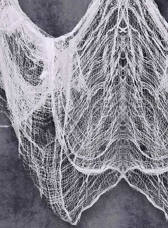 Ein riesiges Dekotuch aus Stoff im Format 2 x 5 Meter, das an klassische weiße Gaze erinnert, ist vor einem grauen, strukturierten Hintergrund drapiert, wobei locker gewebte Fäden in schichtartigen, netzartigen Mustern herabhängen.