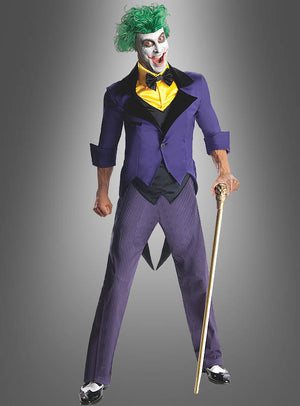Eine Person trägt den Joker-Anzug für Herren, bestehend aus grünen Haaren, weißer Gesichtsbemalung, einem lila Sakko, einer gelben Weste und einer gestreiften Hose, hält einen goldenen Stock in der Hand und steht vor einem grauen Hintergrund.