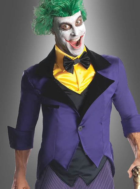Eine Person, die einen Joker-Anzug für Herren trägt, mit grünen Haaren, weißer Gesichtsbemalung, einem gelben Hemd, einer schwarzen Fliege und einem violetten Sakko vor grauem Hintergrund – ideal für Fans, die auf der Suche nach einem authentischen Kostüm sind, das vom legendären Batman-Lizenzkostüm inspiriert ist.