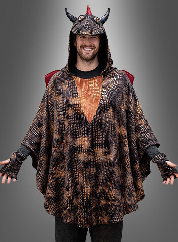 Eine Person trägt den „Drachen Poncho Erwachsene“ – einen Unisex-Poncho mit Kapuze, die mit Hörnern und einem roten Wappen verziert ist – und steht vor einem grauen Hintergrund mit Farbverlauf.