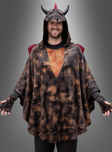 Eine Person trägt den „Drachen Poncho Erwachsene“ – einen Unisex-Poncho mit Kapuze, die mit Hörnern und einem roten Wappen verziert ist – und steht vor einem grauen Hintergrund mit Farbverlauf.