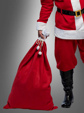 Eine als Weihnachtsmann verkleidete Person hält den „Weihnachtsmann-Geschenkesack 100 x 60 cm“ vor einem grauen Hintergrund in der Hand.