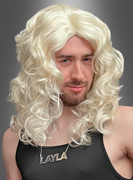 Eine Person, die die „Layla-Perücke, blond mit Locken“ trägt, kombiniert mit einem schwarzen Oberteil und einer Halskette mit der Aufschrift „LAYLA“, vor einem grauen Hintergrund.