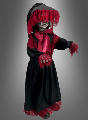 Die Halloween-Puppe „90 cm, gruselig animiert“ steht vor einem grauen Hintergrund mit Farbverlauf und trägt ein schwarzes Kleid mit roter Spitzenborte und einem Schleier. Sie hat leuchtende Augen, ein blasses Gesicht und ausgestreckte Hände.