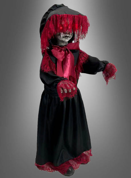 Die Halloween-Puppe „90 cm, gruselig animiert“ steht vor einem grauen Hintergrund mit Farbverlauf und trägt ein schwarzes Kleid mit roter Spitzenborte und einem Schleier. Sie hat leuchtende Augen, ein blasses Gesicht und ausgestreckte Hände.