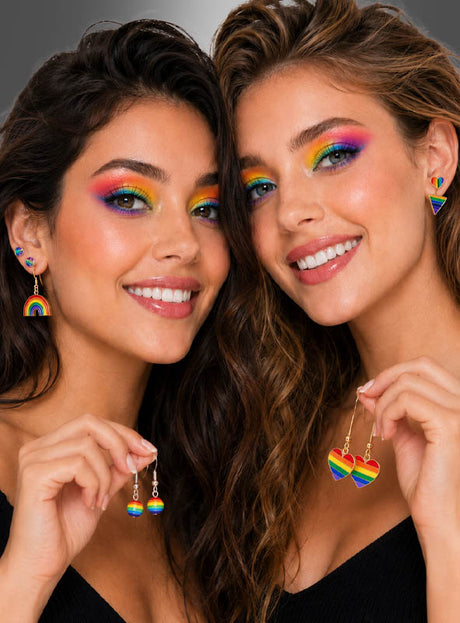 Zwei Frauen mit Regenbogen-Augen-Make-up und langen, gewellten Haaren lächeln und posieren dicht beieinander vor einem dunklen Hintergrund mit Farbverlauf, wobei sie das Set aus 6 Paar Regenbogen-Ohrringen in der Hand halten bzw. tragen. Ihre leuchtend bunten Ohrstecker runden ihren fröhlichen Look perfekt als Pride-Accessoire ab.