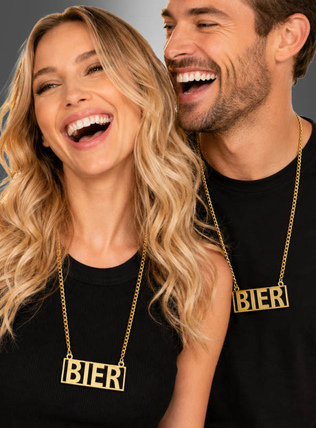 Zwei Menschen, die schwarze Oberteile und „Goldene Bierkette“-Partyschmuck-Halsketten mit dem Wort „BIER“ in großen Blockbuchstaben tragen, lächeln und lachen gemeinsam – ein perfektes Beispiel dafür, wie diese festliche Halskette jeder Feier eine fröhliche Note verleihen kann.