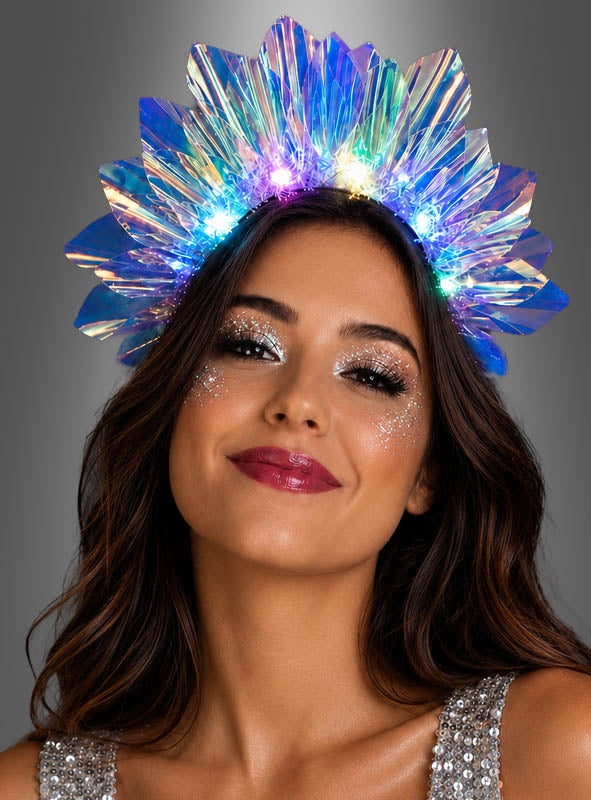 Eine Frau, die eine glänzende Krone mit LED-Lichtern und Glitzer-Make-up trägt und leicht lächelt. Ihr schillernder LED-Haarreif mit Licht verleiht ihrem Look eine verspielte Note und macht sie bereit für jede Party oder den Karneval. Der Hintergrund ist schlicht grau.