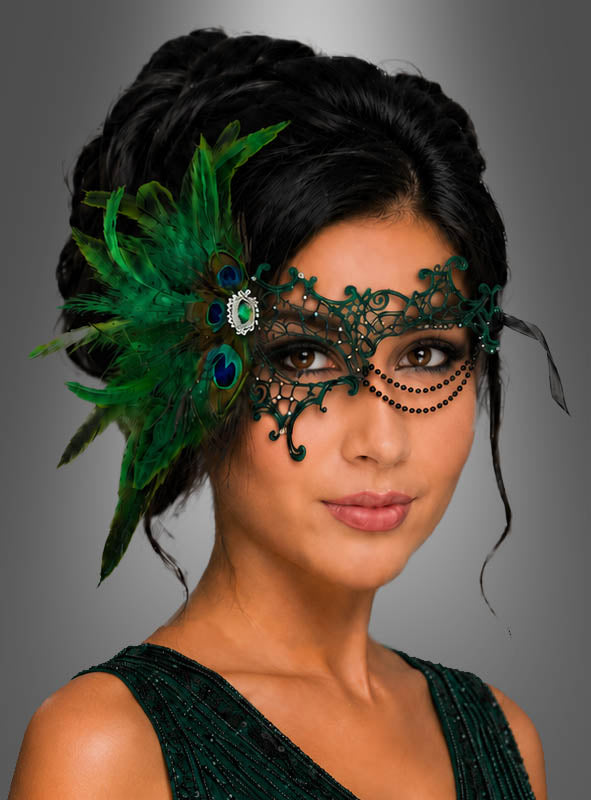 Eine Frau trägt eine filigrane Augenmaske mit Pfauenfedern und ein dunkelgrünes Kleid; ihr Haar ist elegant hochgesteckt und hebt sich von einem grauen Hintergrund mit Farbverlauf ab – ein perfekter Look für einen glamourösen Maskenball.