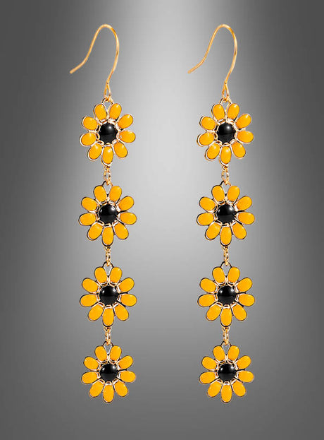 Ein Paar goldene Haken-Ohrringe mit drei vertikal aneinandergereihten, gelb-schwarz emaillierten Blumen in Sonnenblumenform vor einem grauen Hintergrund mit Farbverlauf – eine bezaubernde Wahl für alle, die Lange Blumenohrringe Sonnenblumen lieben oder Fans von Boho-Ohrringen und Hippie-Schmuck sind.