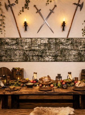 Ein rustikaler Holztisch, gedeckt für ein Festmahl im mittelalterlichen Stil mit gebratenem Fleisch, Obst und Trinkbechern, wird ergänzt durch Schwerter und Äxte, die an einer Steinwand befestigt sind, die im Hintergrund mit der beeindruckenden „Steinmauer Wanddeko aus Stoff 80 x 400 cm“ verziert ist – eine ideale Ergänzung für Ihre Halloween-Dekoration.
