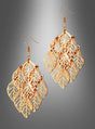 Die „Ohrringe Blätter filigran gold“ sind goldfarbene Ohrhänger, die mit mehrschichtigen, blattförmigen Anhängern und filigranen Golddetails verziert sind. Sie strahlen einen Boho-Stil aus und werden vor einem grauen Hintergrund mit Farbverlauf präsentiert.