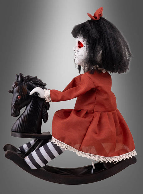 Die 38 cm große Horror-Puppe auf einem Schaukelpferd sitzt mit ihrem schwarzen Haar, den roten Augen und einem roten Kleid auf einem schwarzen Schaukelpferd. Die Geisterpuppe trägt gestreifte schwarze und weiße Strümpfe sowie eine rote Schleife im Haar – die perfekte Halloween-Dekoration für ein gruseliges Ambiente.