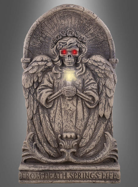 Die „Grabstein 63 cm Engel mit Licht & Ton Deko“ ist eine auffällige Halloween-Dekoration und besteht aus einer Engelsstatue aus Stein mit einem Totenkopfgesicht und leuchtend roten Augen, die ein strahlendes Objekt umklammert; auf dem Sockel steht die Aufschrift „FROM DEATH SPRINGS LIFE“.