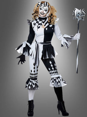 Eine Person, die das „Harlekin Clown für Damen“-Kostüm trägt – mit Rüschenärmeln, einer passenden Maske und einem Narrenstab –, steht vor einem schlichten grauen Hintergrund.
