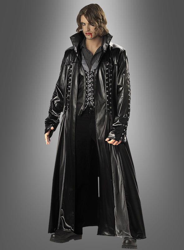 Eine Person in einem langen schwarzen Ledermantel, einer schwarzen Hose und einem dunklen Hemd, mit Reißzähnen und Blut am Mund, steht vor einem einfarbigen grauen Hintergrund – ein markanter Look, der perfekt zum Vampir-Herrenkostüm passt.