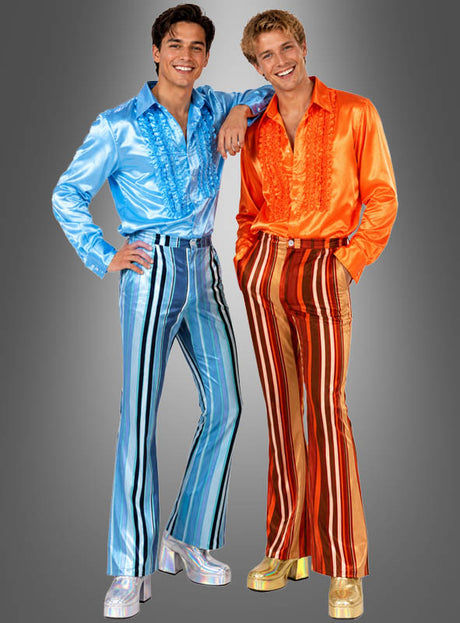 Zwei Männer posieren vor einem schlichten grauen Hintergrund und tragen glänzende, farbenfrohe Outfits im Stil der 1970er Jahre – perfekt für eine Disco-Motto-Party –, darunter Rüschenhemden, Plateauschuhe und gestreifte Schlaghosen für Herren.