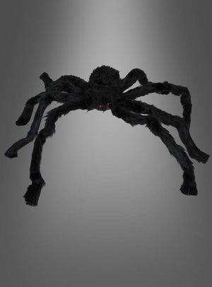 Eine große, schwarze, flauschige Spinne (30–90 cm) als Halloween-Dekoration mit leuchtend roten Augen hebt sich eindrucksvoll von einem schlichten grauen Hintergrund ab – perfekt, um mit Ihren Halloween-Spinnen eine gruselige Atmosphäre zu schaffen.
