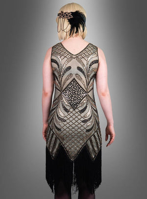 Eine Person, die das „Glamouröses Flapper Kleid Vivian“ trägt – ein mit Perlen besticktes Kleid im Stil der 1920er Jahre mit geometrischem Muster und schwarzen Fransen –, von hinten gesehen und mit einem Feder-Stirnband ergänzt, ist ein atemberaubendes Beispiel für die Mode der 20er Jahre.