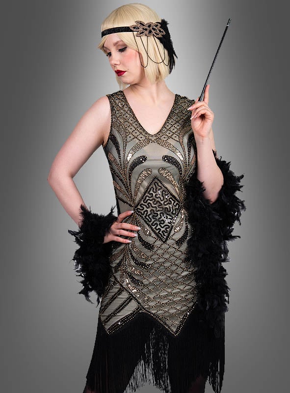 Eine Frau, gekleidet im glamourösen Flapper-Kleid „Vivian“ – mit einem mit Federn verzierten Stirnband, einem schwarz-goldenen Kleid und einer schwarzen Federboa – hält eine Zigarettenspitze in der Hand und verkörpert vor einem grauen Hintergrund die Eleganz der Mode der 20er Jahre.