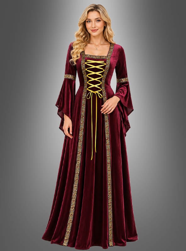 Eine Frau in einem burgunderroten Mittelalterkleid „Hildegard“ – rot oder grün – mit Goldstickerei und einer gelben Schnürung vorne (Kleid mit Schnürung), die vor einem grauen Hintergrund mit Farbverlauf steht.
