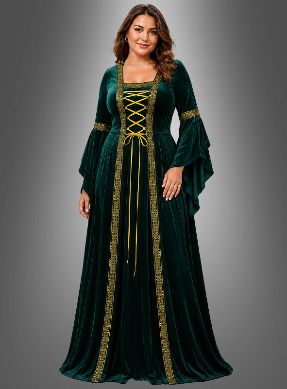 Eine Frau, die das Mittelalterkleid „Hildegard“ in Dunkelgrün mit goldenen Verzierungen, einer Schnürung vorne und ausgestellten Ärmeln trägt, steht vor einem grauen Hintergrund mit Farbverlauf.
