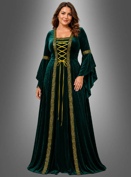 Eine Frau, die das Mittelalterkleid „Hildegard“ in Dunkelgrün mit goldenen Verzierungen, einer Schnürung vorne und ausgestellten Ärmeln trägt, steht vor einem grauen Hintergrund mit Farbverlauf.