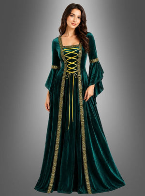 Eine Frau trägt das Mittelalterkleid „Hildegard“ in Grün mit goldenen Verzierungen und einer gelben Schnürung vorne (Kleid mit Schnürung) und steht vor einem schlichten grauen Hintergrund mit Farbverlauf.