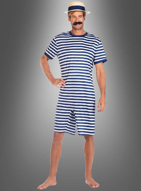 Ein Mann steht barfuß vor einem grauen Hintergrund mit Farbverlauf und trägt den „Gestreiften Schwimmanzug der 20er Jahre“ – einen blau-weiß gestreiften kurzärmeligen Strampler –, dazu einen Strohhut und einen falschen Schnurrbart.